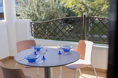a table with four wine glasses on a balcony at Golden Sands Apartment - Chiclana de la frontera in Novo Sancti Petri