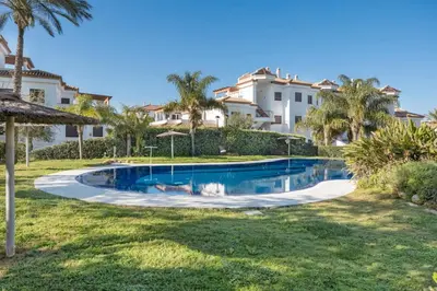 a swimming pool in front of a villa at Golden Sands Apartment - Chiclana de la frontera in Novo Sancti Petri