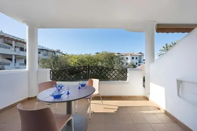 a patio with a table and chairs on a balcony at Golden Sands Apartment - Chiclana de la frontera in Novo Sancti Petri