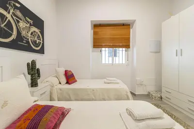 a white room with two beds and a window at Apartamento Santa Clara 1 in Jerez de la Frontera