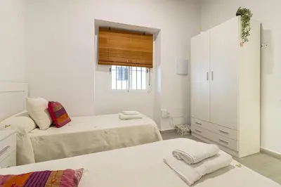 a white bedroom with two beds and a window at Apartamento Santa Clara 1 in Jerez de la Frontera