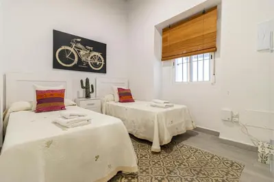 a bedroom with two beds and a picture of a bike on the wall at Apartamento Santa Clara 1 in Jerez de la Frontera