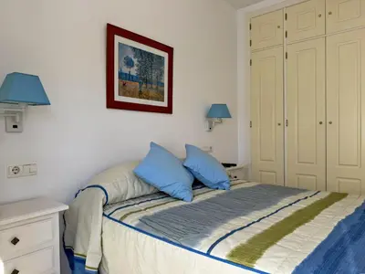 a bedroom with a bed with two blue pillows at Apartamento Albatros - Ole Solutions in Sanlúcar de Barrameda