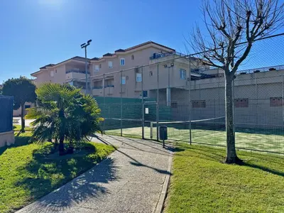 a tennis court with a fence in front of a building at Apartamento Albatros - Ole Solutions in Sanlúcar de Barrameda
