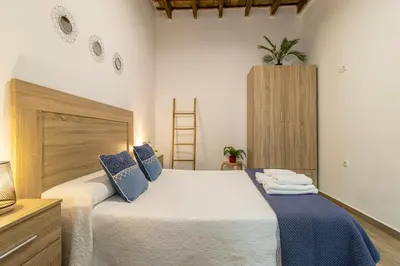 a bedroom with a large bed with blue pillows at Apartamento Santa Clara 3 in Jerez de la Frontera