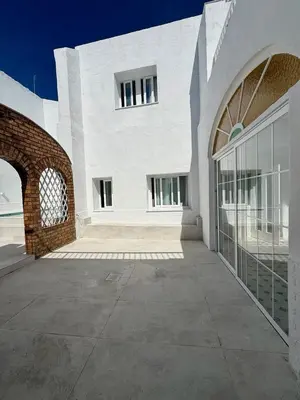 a white building with an archway next to a building at Villa Palacio con Piscina Privada in Puerto Real