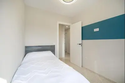 a white bed in a room with a blue accent wall at Agua Marina by Staycare in Rota