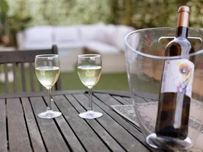 a bottle of wine and two glasses on a wooden table at Arrecife Home by Staycare in Rota