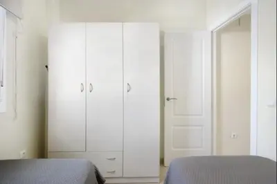 a bedroom with two beds and white cabinets at Budha Candor free parking by Staycare in Rota