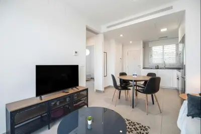 a living room with a flat screen tv and a table at Dunas Candor free parking by Staycare in Rota