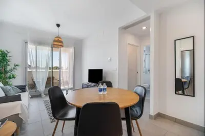 a dining room and living room with a table and chairs at Dunas Candor free parking by Staycare in Rota