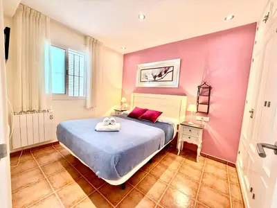 a bedroom with a bed and a pink wall at V Centenario free parking by Staycare in Rota