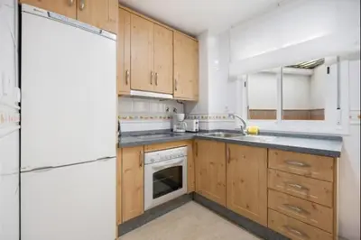 a kitchen with wooden cabinets and a white refrigerator at Girasoles Rota by Staycare in Rota