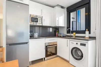 a kitchen with white cabinets and a washer and dryer at La Atalaya free parking by Staycare in Rota