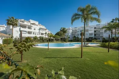 a large swimming pool with palm trees and buildings at La Atalaya free parking by Staycare in Rota