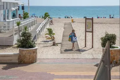a woman walking down a path to the beach at Ecija Playa Rota by Staycare in Rota