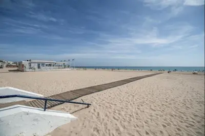 a sandy beach with a building and the ocean at Ecija Playa Rota by Staycare in Rota