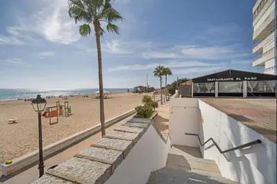 a beach with a palm tree and a playground at Pinar del Mar by Staycare in Rota