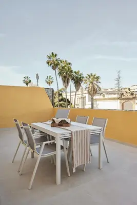 a white table and chairs on a patio with palm trees at Wehost - Costaluz APARTAMENTO JAZMINES in El Puerto de Santa María