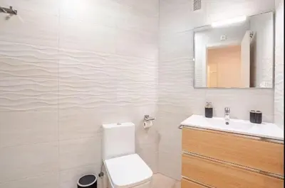 a white bathroom with a toilet and a sink at Piso Cádiz Playa Victoria in Cádiz