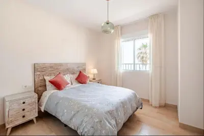 a white bedroom with a large bed with red pillows at Piso Cádiz Playa Victoria in Cádiz