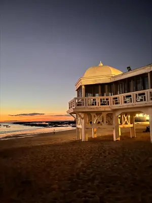 a large building on the beach at sunset at Cádiz, ciudad y playa in Cádiz