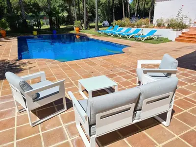 a pool with two lounge chairs and a table next to it at Villa Serena - Casa rural en Arcos con piscina, barbacoa, chimenea in Arcos de la Frontera