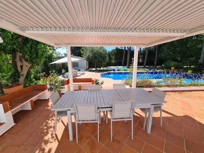 a wooden table and chairs under a white umbrella at Villa Serena - Casa rural en Arcos con piscina, barbacoa, chimenea in Arcos de la Frontera