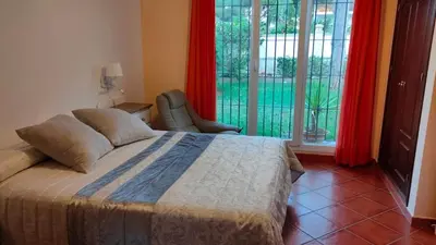a bedroom with a bed and a window with red curtains at Villa con piscina junto a la playa in Roche