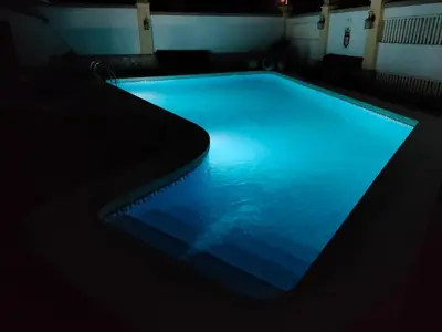 a swimming pool with blue lights in a dark room at Villa con piscina junto a la playa in Roche