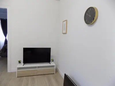 a living room with a tv and a clock on a wall at Plaza del Rey Apartments in San Fernando