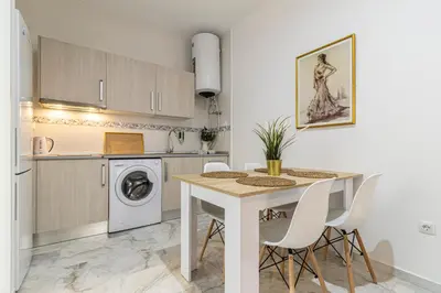 a kitchen with a table and a washing machine at Allo Apartments San Lucas Parking Piscina Centro 2 habitaciones in Jerez de la Frontera