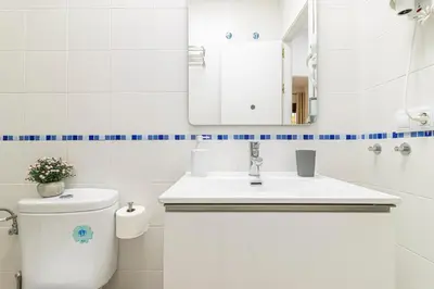 a bathroom with a toilet and a sink and a mirror at Allo Apartments San Lucas Parking Piscina Centro 2 habitaciones in Jerez de la Frontera