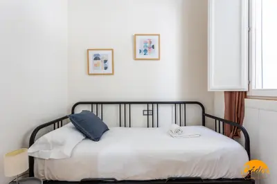 a bedroom with a bed with white sheets at Apartamento El Patio by Cadiz Time in Cádiz