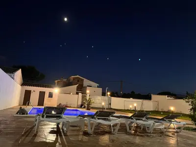 a group of chairs sitting next to a pool at night at Rincón del mar in Novo Sancti Petri