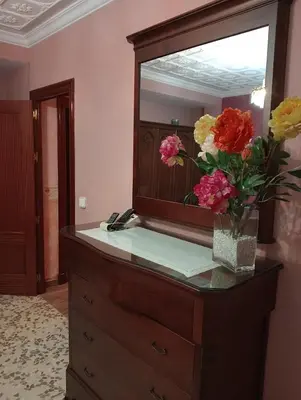 a dresser with a mirror and a vase with flowers on it at Como en casa in Jerez de la Frontera