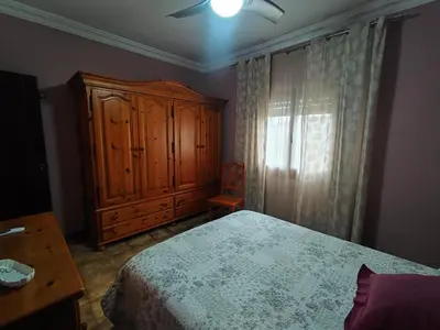 a bedroom with a bed and a wooden cabinet at Encantador chalet con piscina in Conil de la Frontera