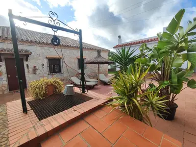 a courtyard of a house with a umbrella and plants at Encantador chalet con piscina in Conil de la Frontera