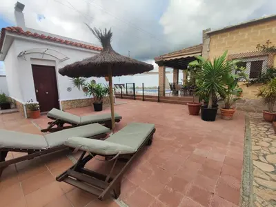 a patio with two lounge chairs and an umbrella at Encantador chalet con piscina in Conil de la Frontera