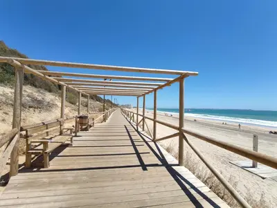 a wooden boardwalk leading down to the beach at MasApartamentos El Puerto in El Puerto de Santa María