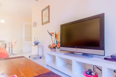 a living room with a large flat screen tv on a white table at MasApartamentos El Puerto in El Puerto de Santa María
