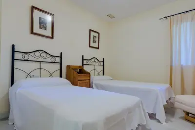 two beds in a room with white sheets at MasApartamentos El Puerto in El Puerto de Santa María