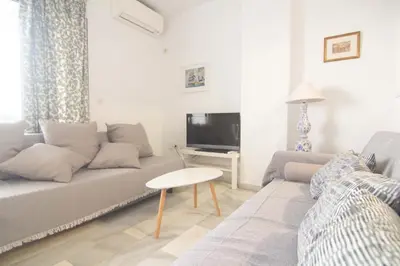 a living room with a couch and a tv at Apartamento Vistahermosa terraza y piscina in El Puerto de Santa María