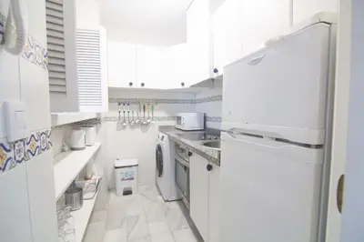 a white kitchen with a refrigerator and a sink at Apartamento Vistahermosa terraza y piscina in El Puerto de Santa María
