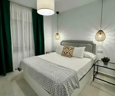 a bedroom with a large bed with white and green curtains at Apartamentos Muñoz Fornell 4 in Chiclana de la Frontera