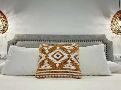 a bed with a brown and white pillow on it at Apartamentos Muñoz Fornell 4 in Chiclana de la Frontera