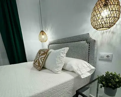 a bedroom with a bed with pillows and a chandelier at Apartamentos Muñoz Fornell 4 in Chiclana de la Frontera
