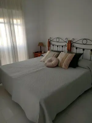 a bedroom with a large white bed with pillows at Ático primera línea en costa ballena in Rota
