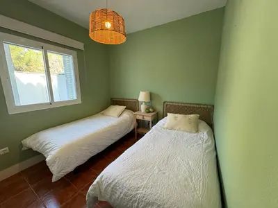 two beds in a room with green walls and a window at Adosado en Novo Sancti Petri in Novo Sancti Petri
