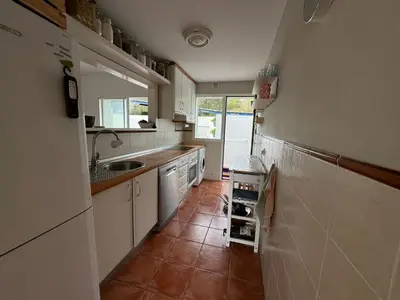 a kitchen with white cabinets and a tile floor at Adosado en Novo Sancti Petri in Novo Sancti Petri